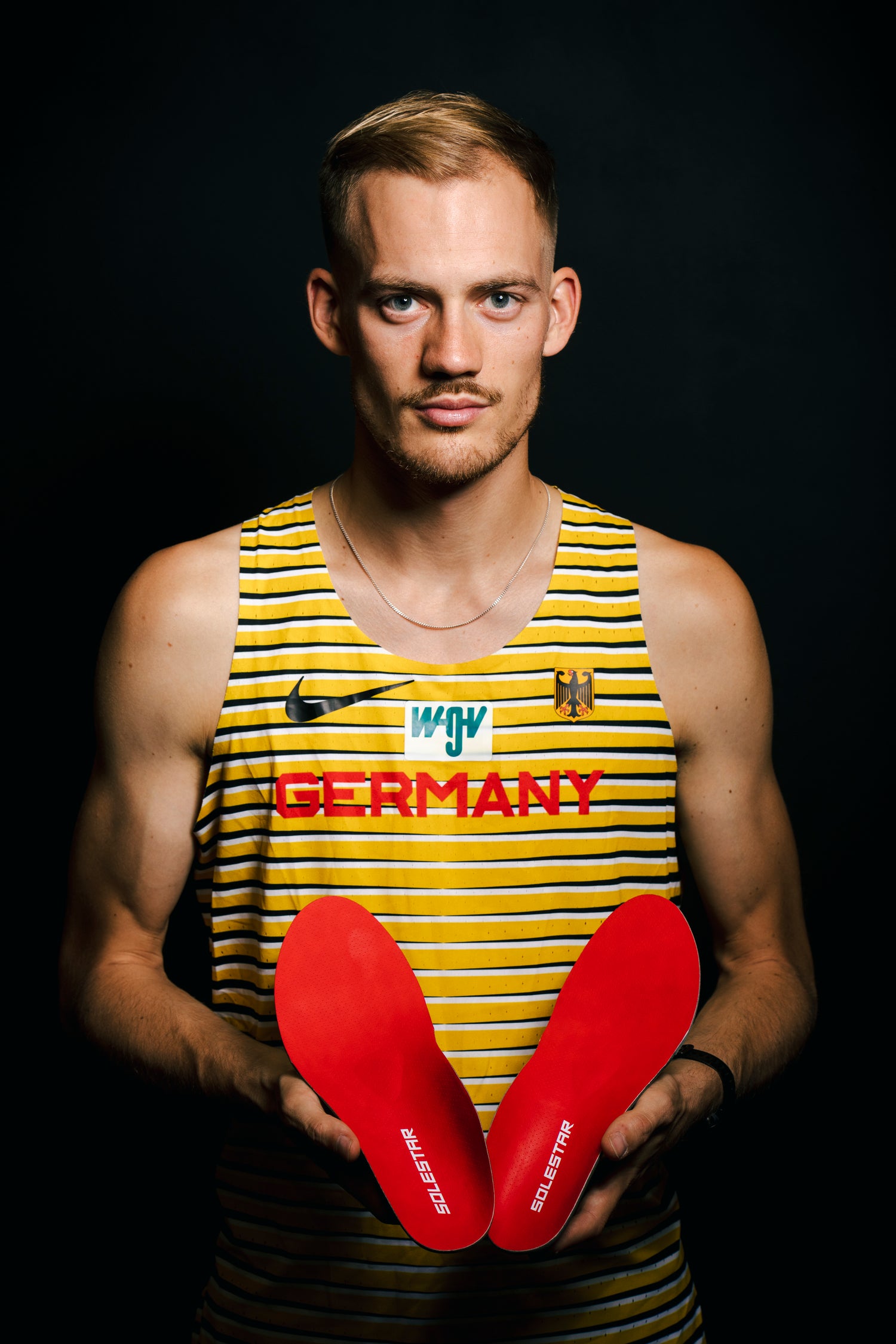 Professional runner wearing Solestar neutral run insoles, on a dark background for photography.