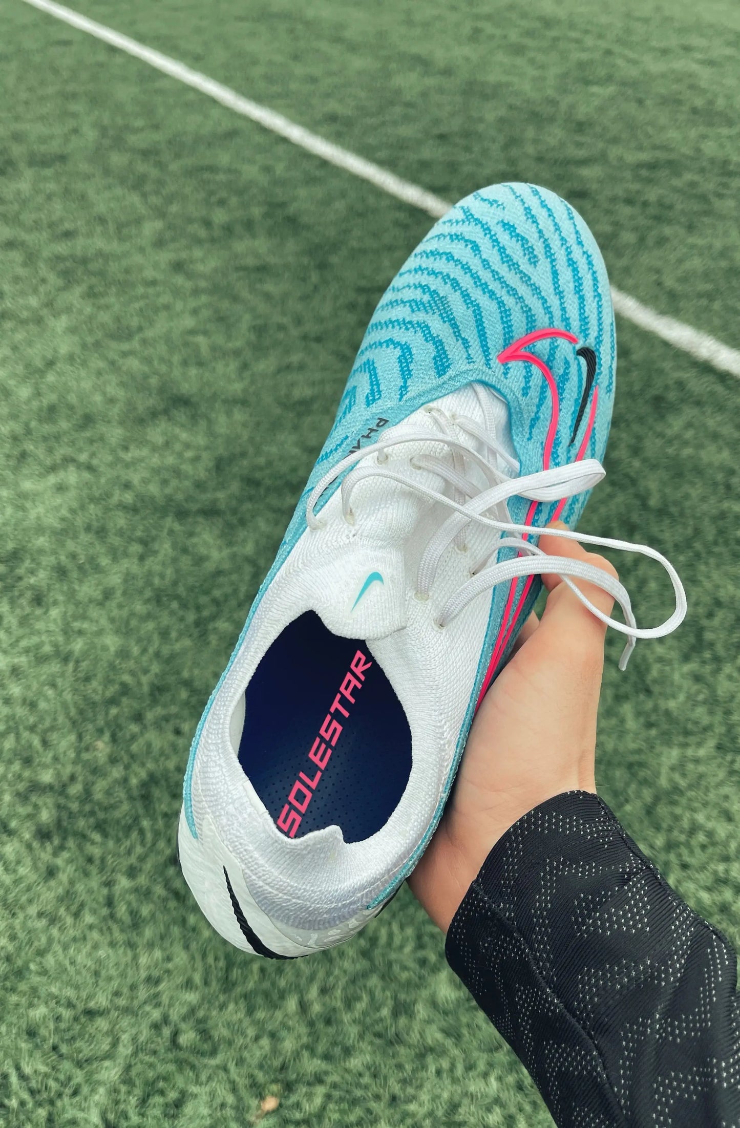 person holding a soccer cleat shoe and inside the shoe is a solestar kick insole.