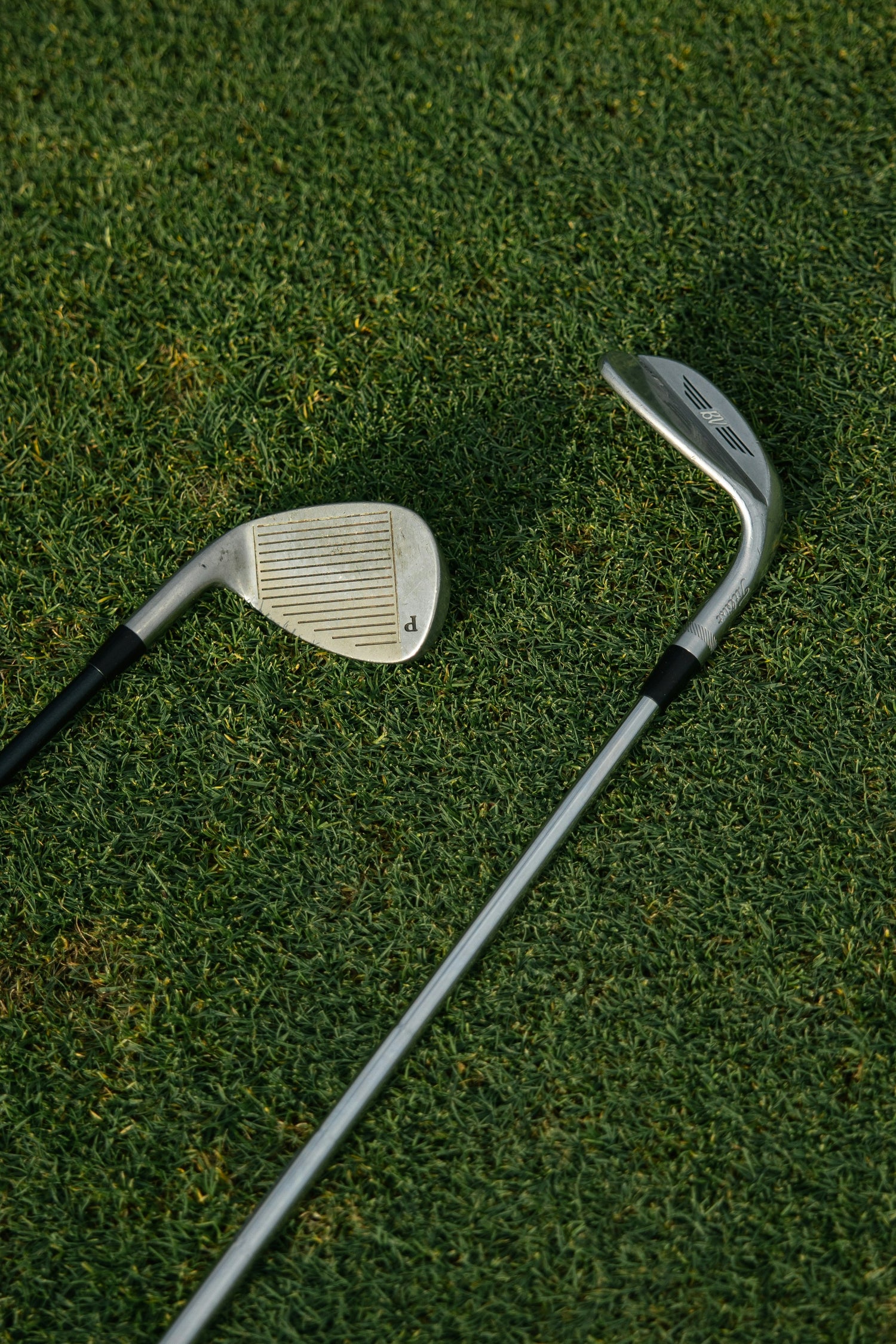 Two golf clubs on a grassy surface