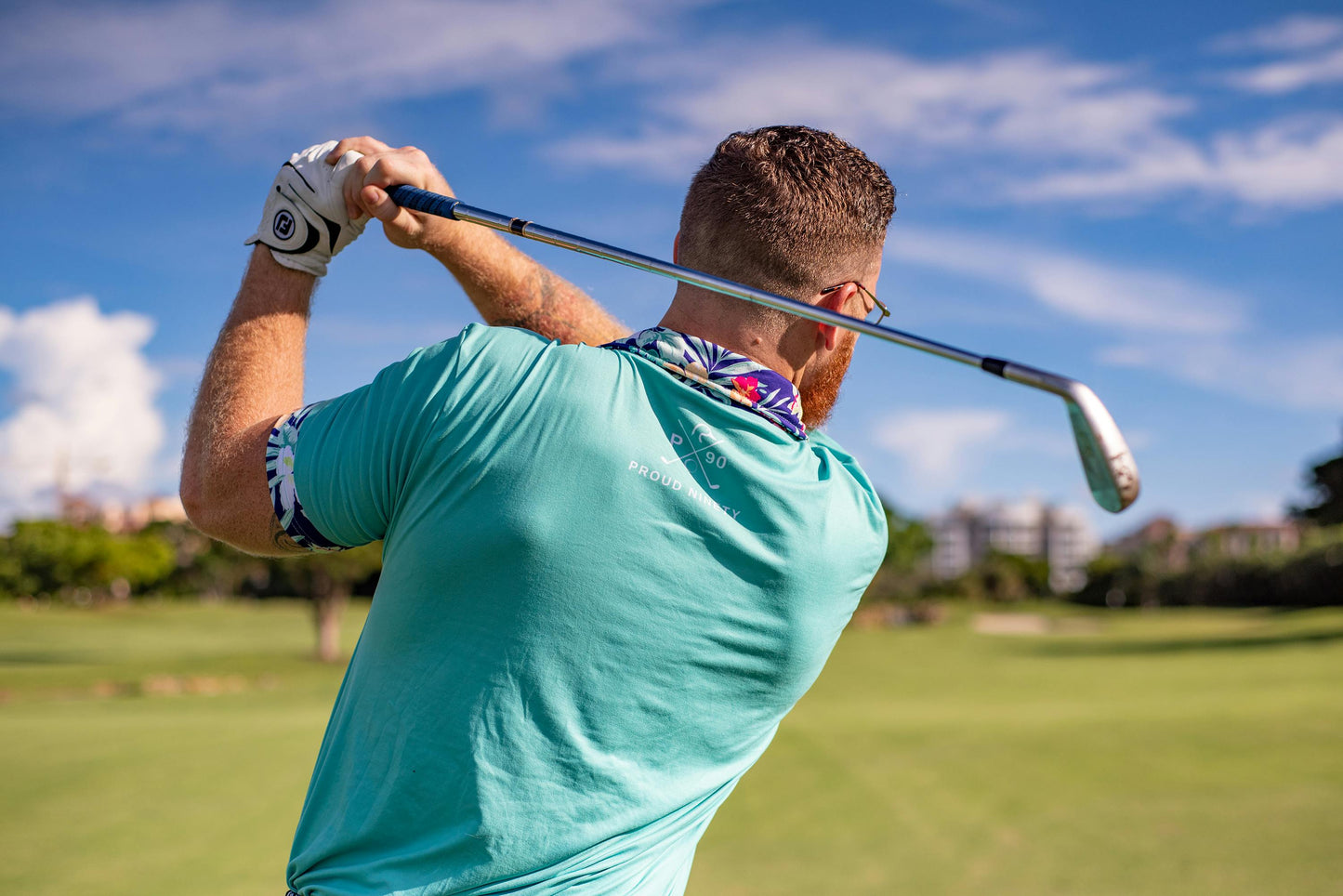 Man playing golf on a sunny day with a blue sky.
