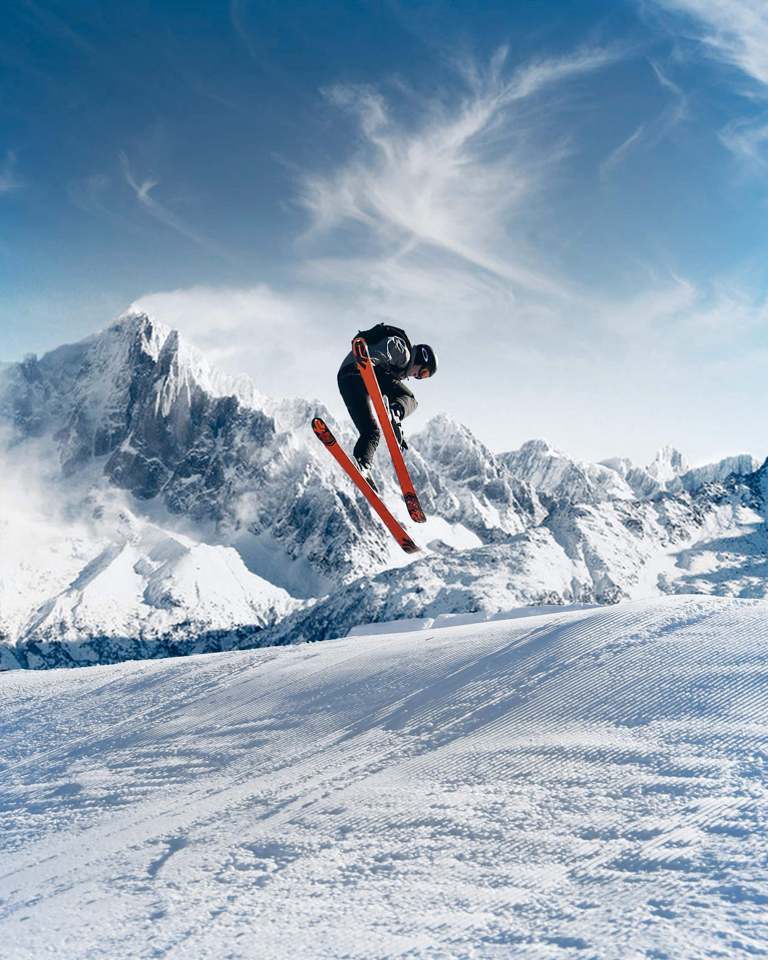Skiier in mid-air against a snowy mountain landscape