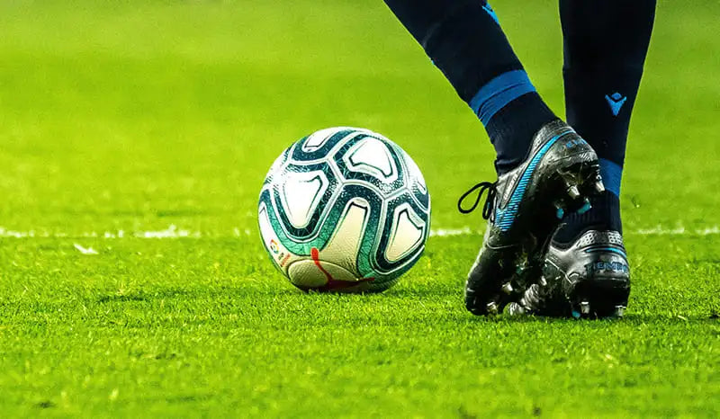 sport insoles- Soccer insoles. in the picture we can see a man using soccer cleats boots and a soccer ball.