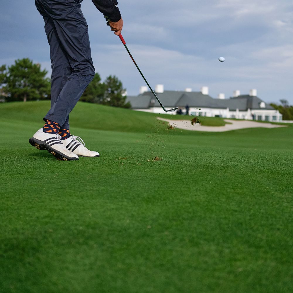 Person playing golf on a green course with a building in the background