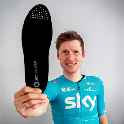 Christian Knees holding a black insole with 'solestar' branding against a gray background