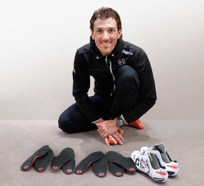 Fabian Cancellara in black outfit with insoles and shoes on a light background