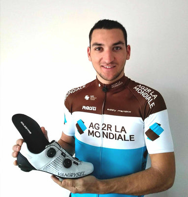 Cyclist Nans Peters holding a cycling shoe insole with 'AG2R LA MONDIALE' branding on a plain background