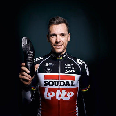 Pro Cyclist Phillippe Gilbert
 in a Soudal Lotto jersey holding a cycling shoe insole against a dark background
